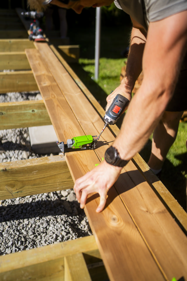 Snickare försänker en dold trallskruv på ett trädäck med hjälp av Hidden Decking verktyget. 