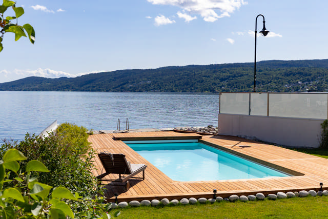 En trall byggd runt en pool med sjäutsikt.