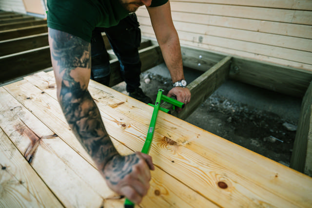 En ESSBOX-väska med skruv ligger på en gräsmatta brevid en sänksåg.